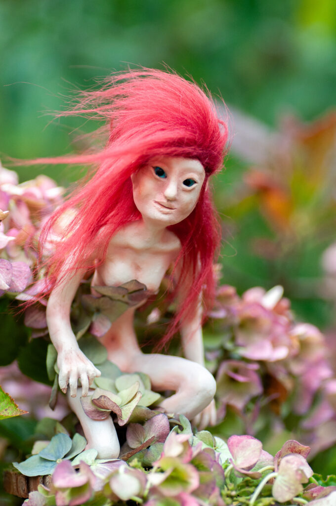 DSC_0056 A handcrafted Nissri fairy figurine named Brynna, posed as if caught mid-dance, her body adorned with moss and dried petals. She stands amid softly lit woodland tones, her wild hair and bright expression evoking the free spirit of Thalorien’s forest canopy.